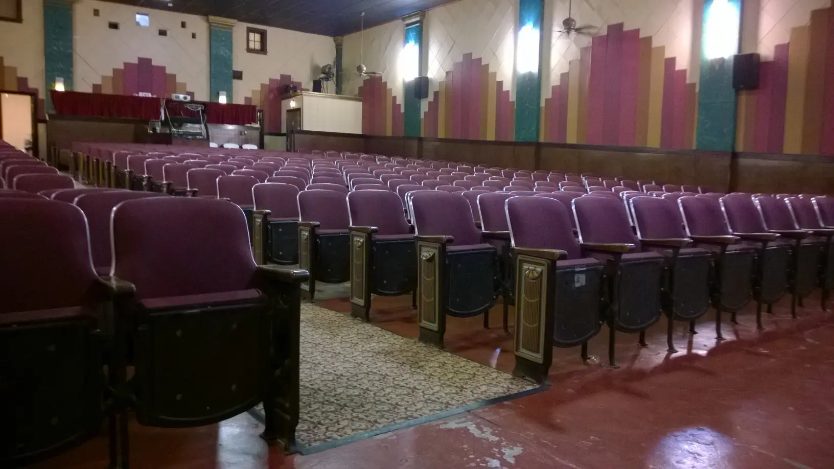 A large auditorium with purple seats and a carpet.